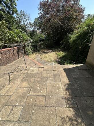 Spacious sunny garden with large stone patio ar...