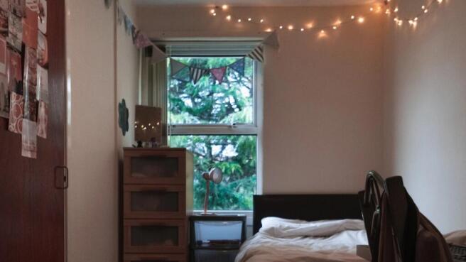 A cozy single bedroom featuring a neatly made b...
