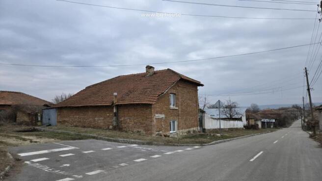 View of the brick house with tiled roof located at a street corner in Katselovo village