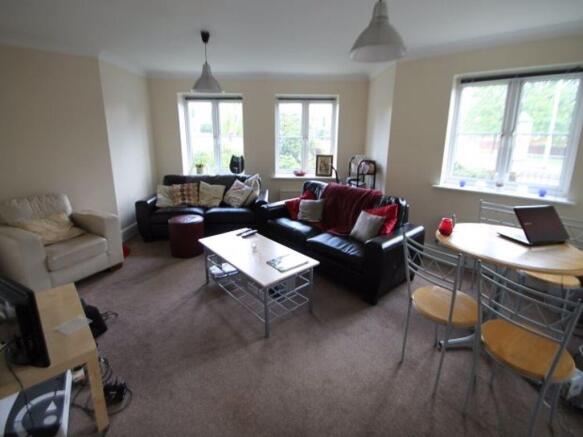 A spacious and well-lit living room featuring a...