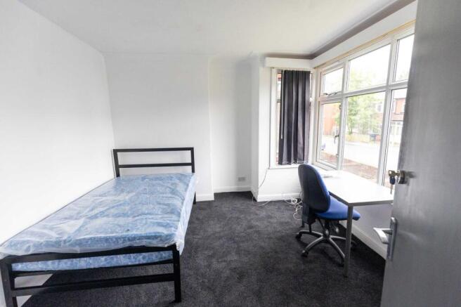 A bright, simple bedroom featuring a single bed...