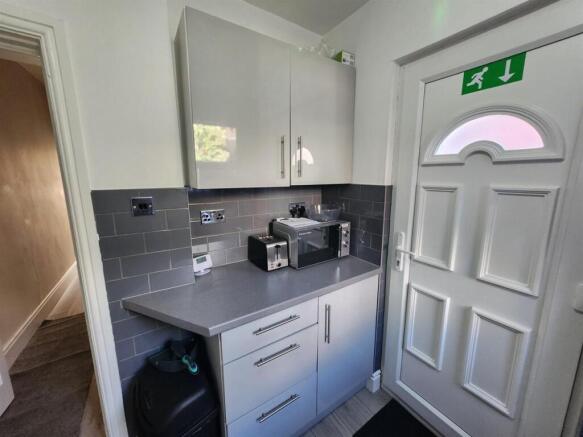 Compact modern kitchen area with grey tiled spl...