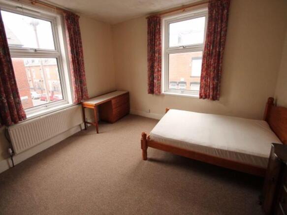 Bright, simply furnished bedroom with two large...
