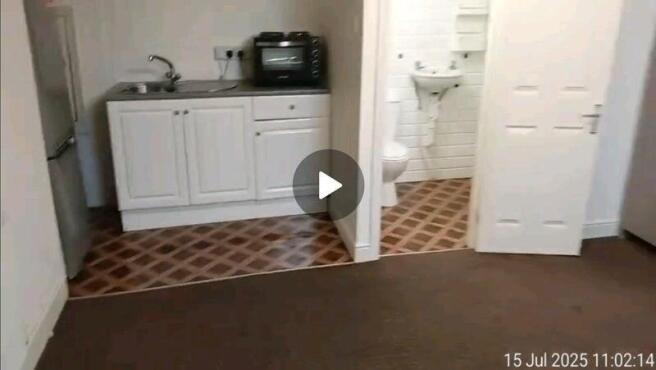 A compact kitchen area featuring white cabinetr...