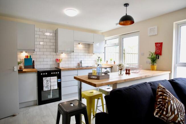 Bright modern kitchen with white cabinetry, sub...