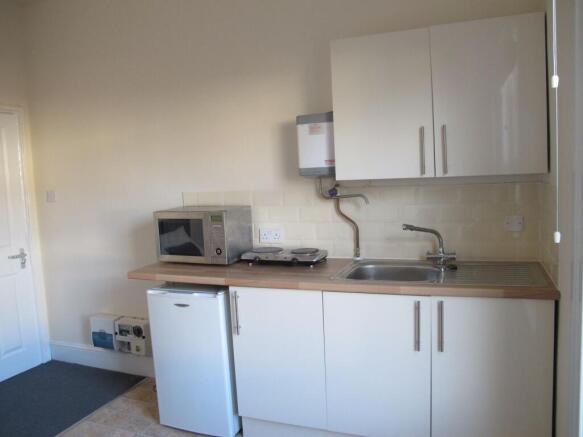Compact modern kitchenette with white cabinets,...