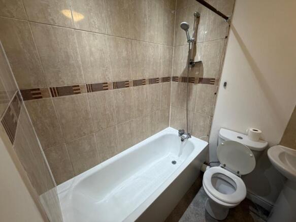Clean, neutral-tiled bathroom with a white bath...