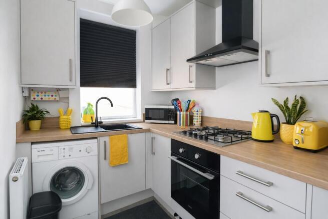 Bright, modern kitchen with white cabinetry, wo...