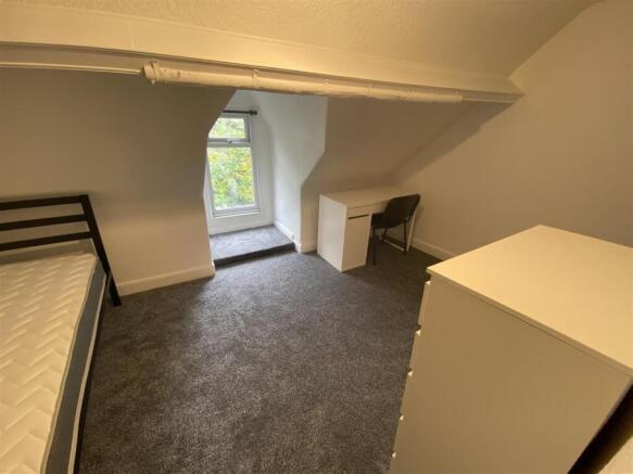 Bright attic bedroom with a desk and leafy view...