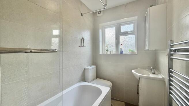 Modern tiled bathroom suite with bath and windo...