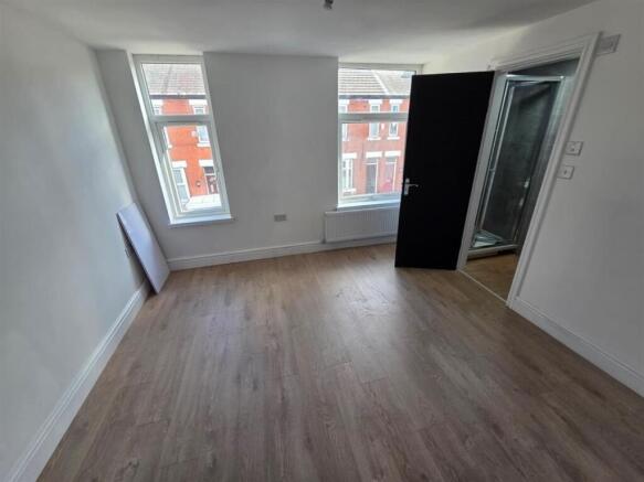 Bright master bedroom with sleek wood flooring...