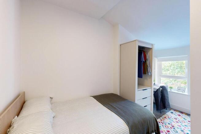 A bright and tidy bedroom with a comfortable be...