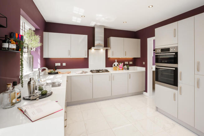 A modern kitchen with light gray cabinets and a purple accent wall features a white countertop with