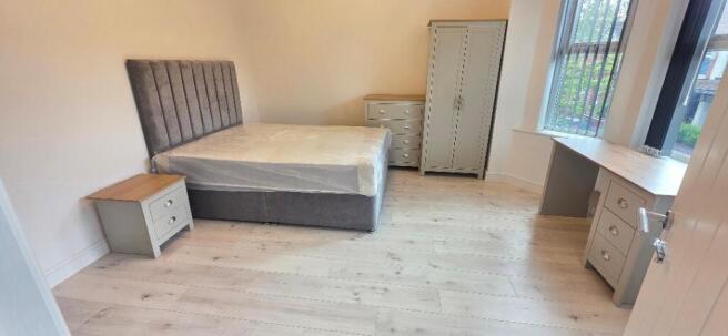 Bright, airy bedroom with a desk and large wind...