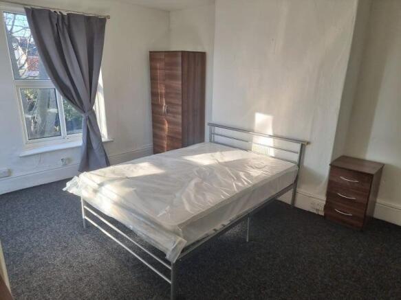 Bright, well-lit bedroom with a metal double be...