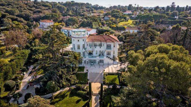 Aerial view of a luxurious white mansion surrounde