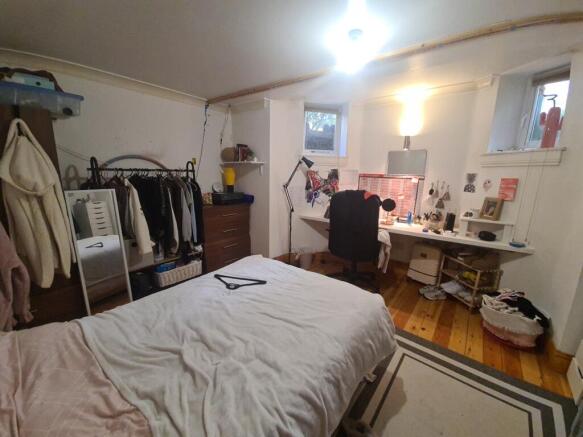 A cozy bedroom with a neatly made bed, a window...