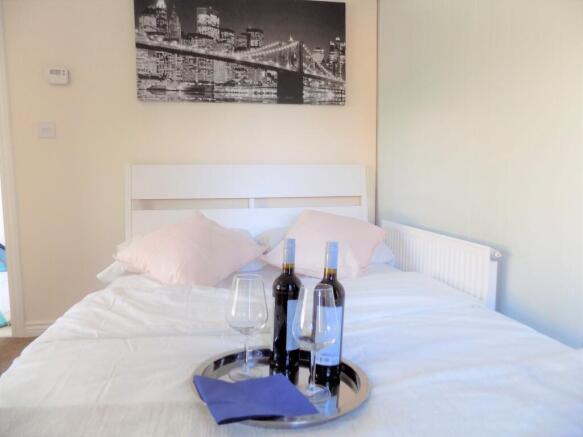 Bright, tidy double bedroom with a white headbo...