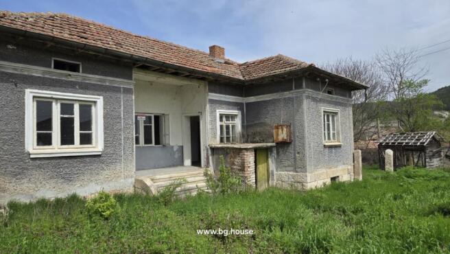 Side perspective of the Bulgarian house with visible windows, tiled roof, and garden space