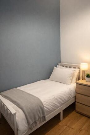 Neat single room with cozy bed and bedside lamp...