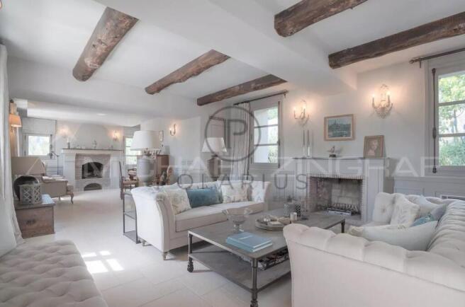 A bright, cozy living room with white sofas, expos