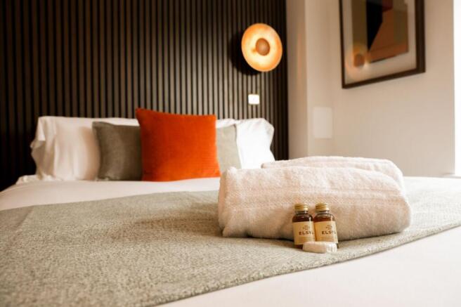 Stylish double bed with cushions and fresh towe...