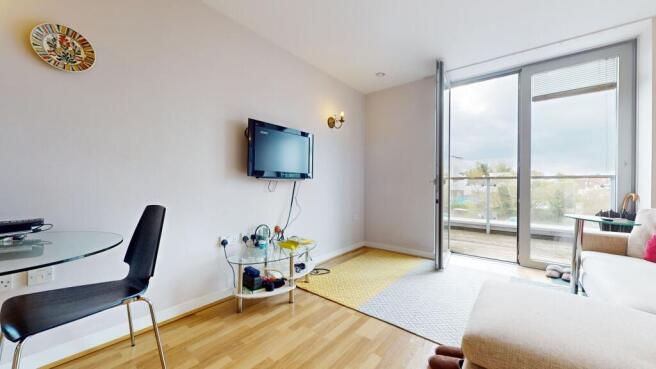 Bright living room with large glass balcony doo...