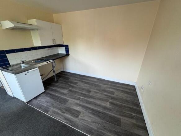 A compact kitchen area featuring basic white ca...