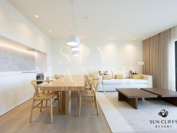 Open plan dining area at Sun Cliffs Resort, Lagos, featuring a wooden table, modern chairs, and a luxury integrated kitchen.