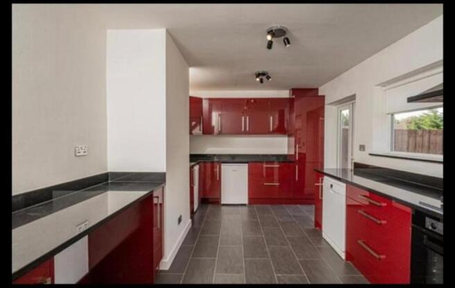 Modern galley kitchen with glossy red cabinetry...