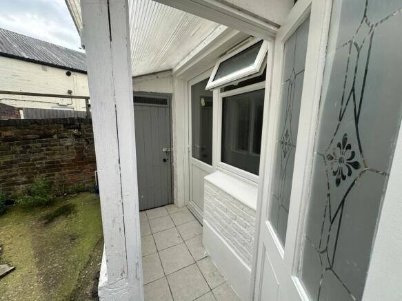 Covered porch/entrance with tiled step and side...