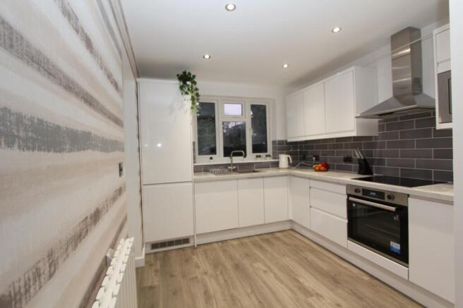 Modern kitchen featuring sleek white cabinetry,...