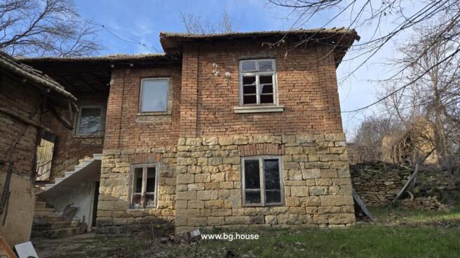 Exterior view of a two-storey house showing stone and brick walls with several windows and an outdoor staircase