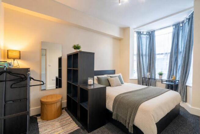 Bright bedroom with large bay window and storag...