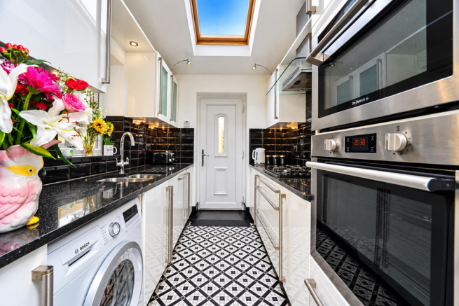 Bright Galley Kitchen with Skylight and Floral Vas