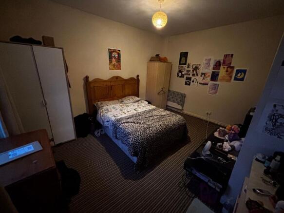 Cosy double bedroom with a wooden headboard, pa...