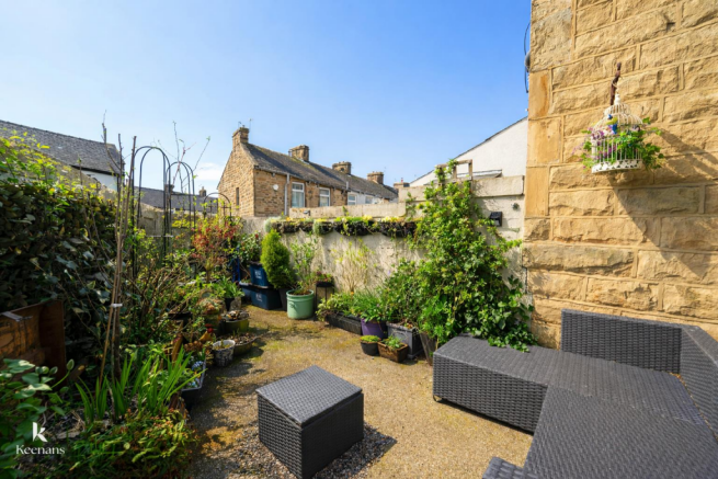 Sunny garden patio with rattan furniture.png