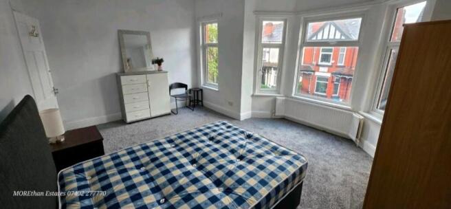 Bright bedroom with large bay window and storag...