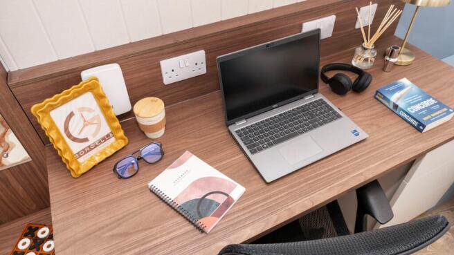 Well-presented wooden desk with a laptop, noteb...