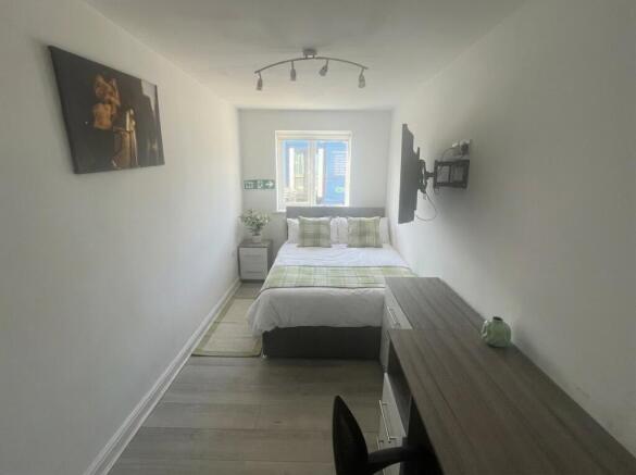 Modern bedroom with a desk and wall-mounted TV...