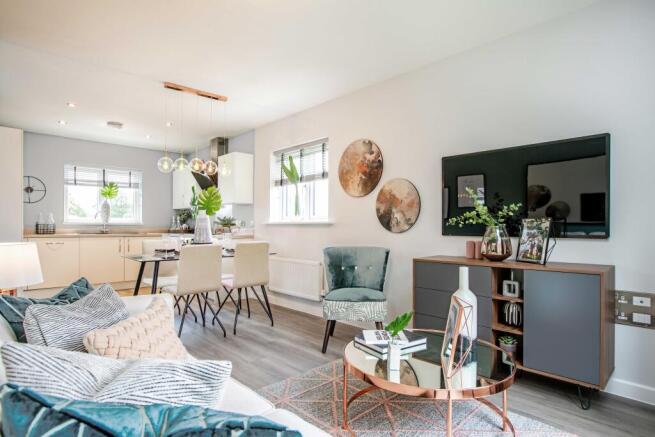 A modern living and dining area with a plush sofa in the foreground and a sleek kitchen in the backg
