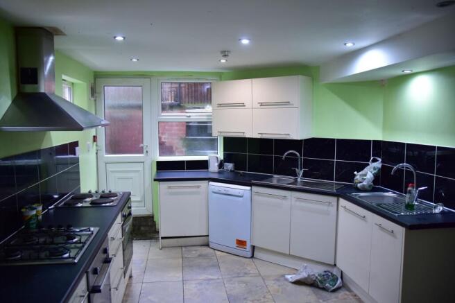 A practical kitchen featuring white cabinetry, ...