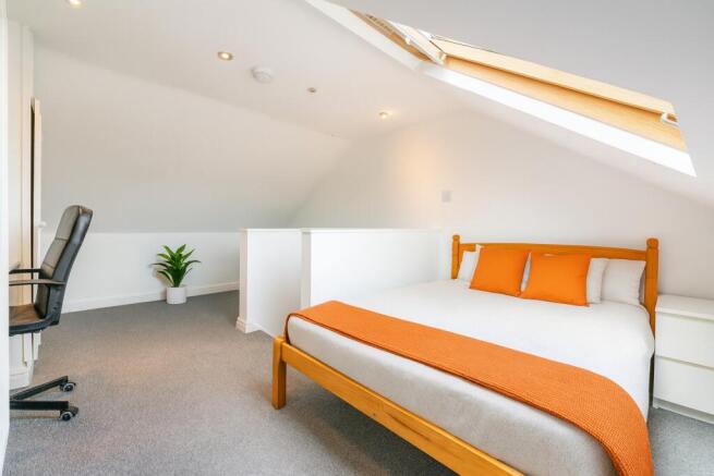 Bright loft bedroom with skylight and study are...