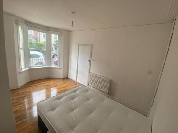Bright bedroom with large bay window and wood f...