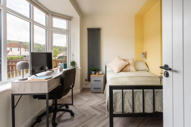 Bright bedroom with bay window and study desk a...