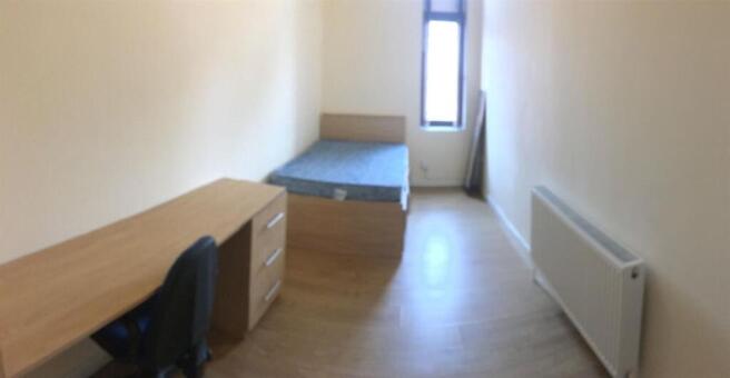 Bright bedroom with large desk and wood floorin...