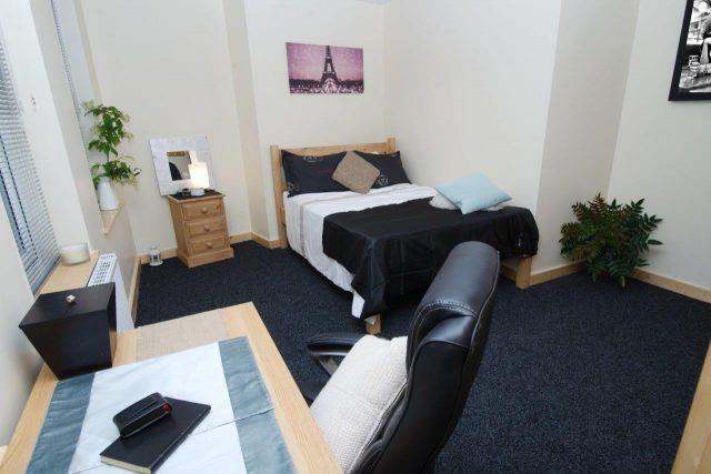 Bright master bedroom with large desk and bed...
