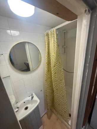 Compact bathroom with round mirror and shower...