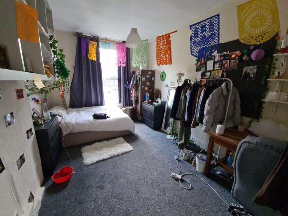 A cozy, well-lit single bedroom featuring a bed...