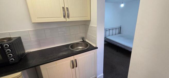 Compact kitchenette with sink and adjoining bed...